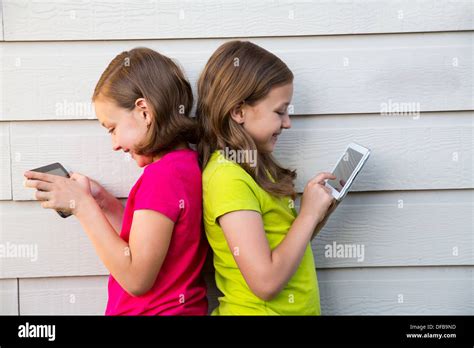 Twin Sister Girls Playing With Tablet Pc Happy On White Wall Leaning On