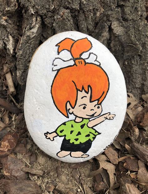 A Painted Rock With A Cartoon Girl On It