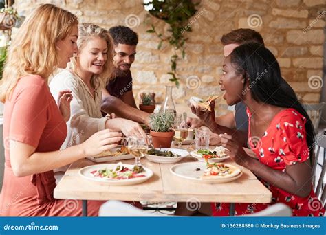 Young Adult Friends Eating Lunch At A Table In A Restaurant Stock Photo