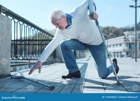 Mature Man Gathering His Crutch Up After Falling Down Stock Photo