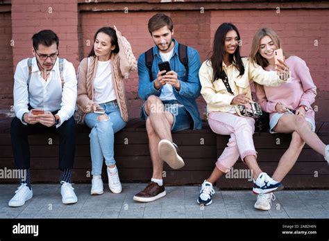 Modern Generation Group Of People Using Gadgets Sitting On Stairs