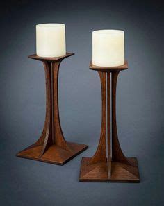 Two Wooden Candlesticks Sitting On Top Of Each Other With One Candle In