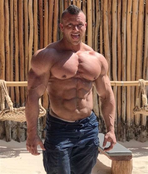 A Shirtless Man Standing In Front Of A Bamboo Fence Holding A Hammer