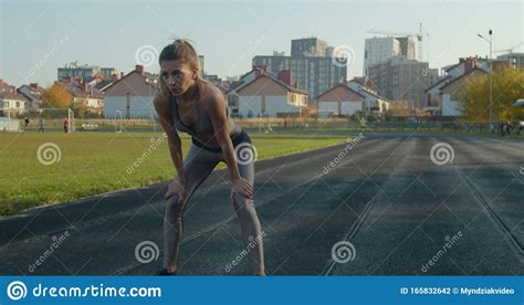 Athletic Blonde Woman Finishing Running And Bending Over To Catch Her
