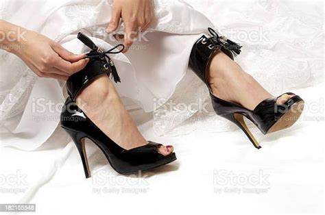 Closeup Of Hands And Feet Of Bride Tying Kinky Shiny Black Heeled Shoes