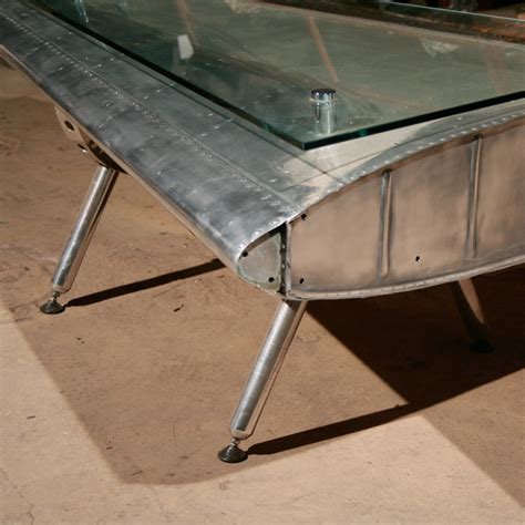 The airplane wing coffee table is handmade from solid wood and plated with spitfire style aluminum making this piece a huge living room talking point. Finnegan Gallery - Airplane Fin Coffee Table