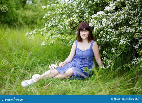 Beautiful Woman Sitting Under Blooming Tree In Summer Garden Stock