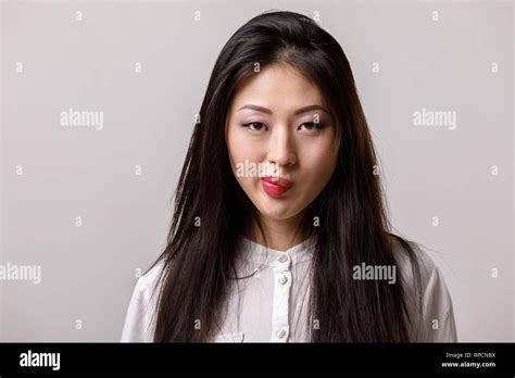 Portrait Of Thinking Asian Woman In Glasses And White Shirt On Gray