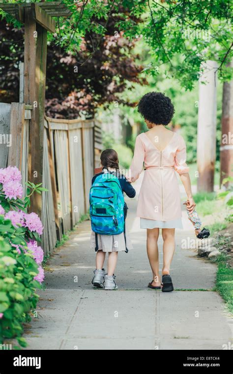 Mixed Race Mother And Daughter Walking On Suburban Sidewalk Stock Photo