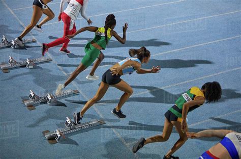 Female Track And Field Athletes Taking Off From Starting Blocks Stock