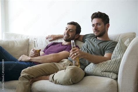 Gay Male Couple On Sofa At Home Watching Tv Drinking Beer Stock Photo Adobe Stock