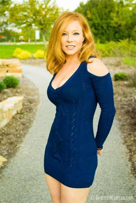A Woman In A Blue Dress Is Posing For A Photo On A Path With Trees And Bushes Behind Her