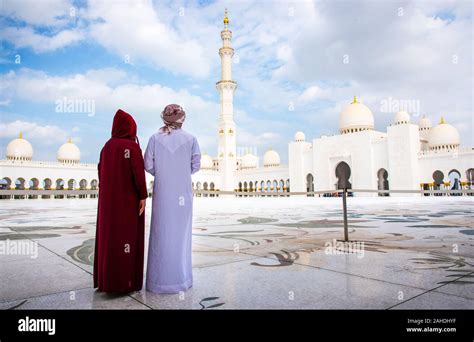 arab couple visiting the grand mosque in abu dhabi wearing traditional dress back view stock