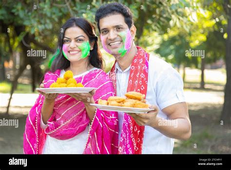 Happy Mature Indian Couple Wearing White Kurta With Plate Of Laddu And