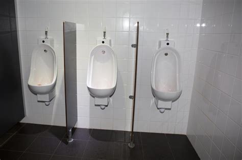 detalhe com três urinóis brancos em um banheiro público masculino foto premium