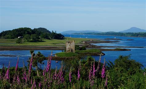 An Old Castle Sitting On Top Of A Lush Green Hillside Next To The Ocean