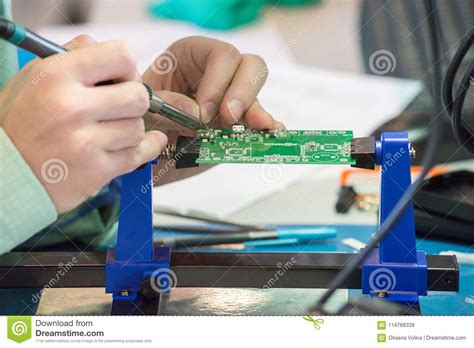A Person Solder The Parts Of The Chip With A Soldering Iron With Stock