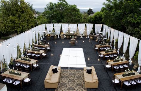 An Outdoor Seating Area With Couches Tables And Lights On The Side Of It