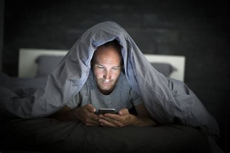Young Cell Phone Addict Man Awake Late At Night In Bed Using Smartphone