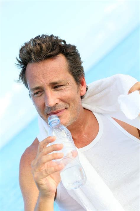 Middle Aged Man Drinking Water After Excersising By The Sea Stock Photo