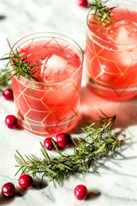 Two Glasses Of Cranberry Bourbon Smash Cocktails Surrounded By Whole