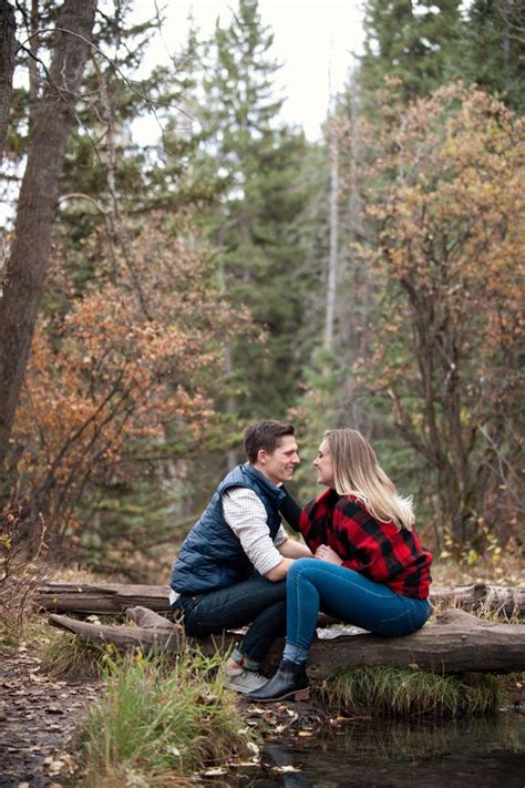 A Man And Woman Sitting On A Log In The Woods By A Stream Looking Into Each Other S Eyes