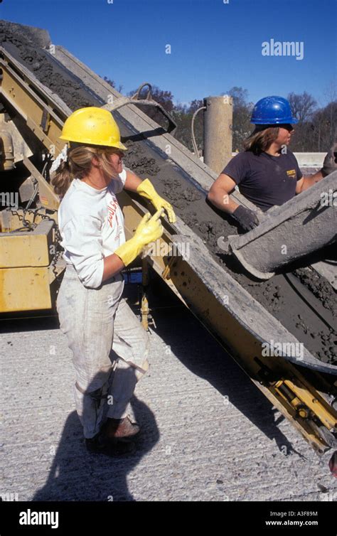 Female And Male Construction Workers Pouring Wet Concrete On New Stock