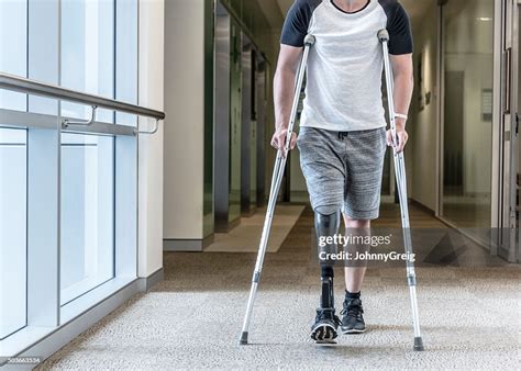 Man With Prosthetic Leg Using Crutches To Walk Down Corridor High Res