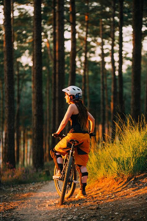 A Woman Mountain Bike Rider Taking A Break On A Forest Path Light By The Sunset Del