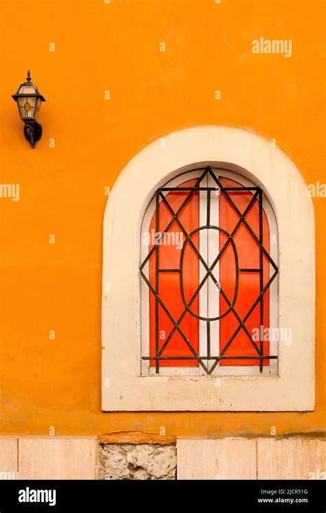 Shuttered Arched Window With Iron Grate Set In Orange Plaster Wall In