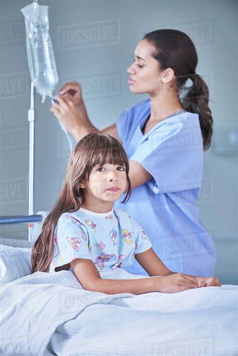 Female Nurse Adjusting Girl Patients Intravenous Drip In Hospital
