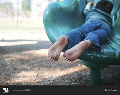 View Of Childs Dirty Bare Feet As He Slides Down A Playground Slide