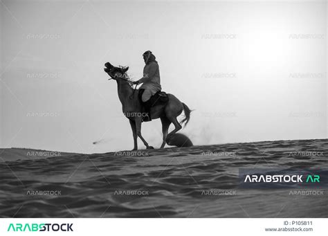 صورة بالاسود والابيض لخيال عربي خليجي سعودي يرتدي الشماغ والزي التقليدي يمتطي فرسه في وضح النهار