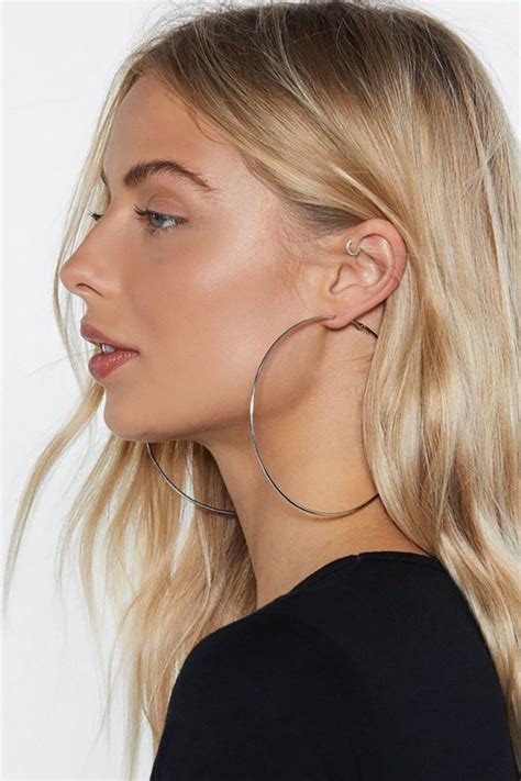 A Woman With Blonde Hair Wearing Large Hoop Earrings And A Black T