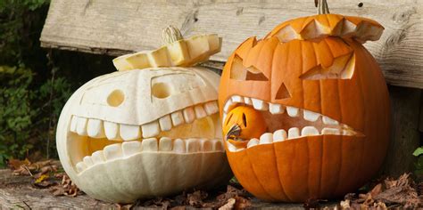 Two Carved Pumpkins Sitting On Top Of Leaves Next To Each Other One