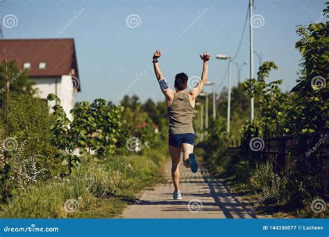 A Male Runner Runs With His Arms Raised In The Park Stock Image