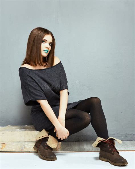 Portrait Of Fashion Full Body Model Seating Against Gray Wall Stock