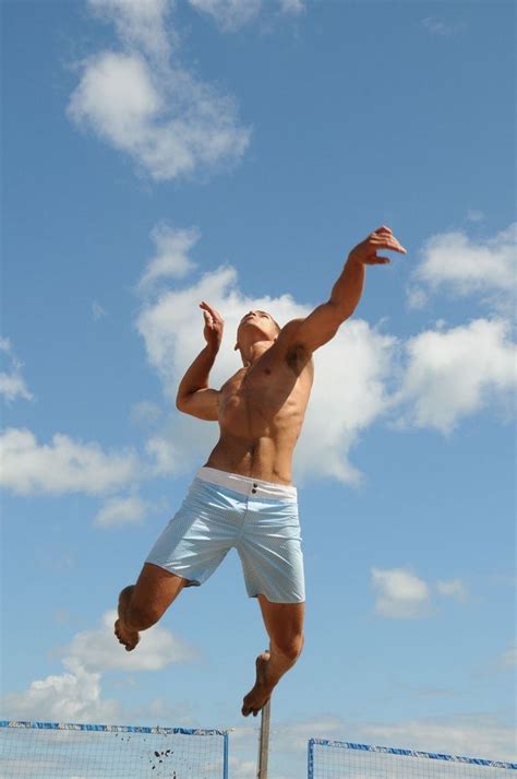 A Man Jumping In The Air To Catch A Frisbee On Top Of A Beach