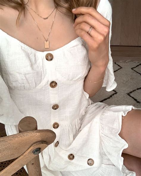 A White Flowy Dress With Buttons Down The Front To Give It Some Style