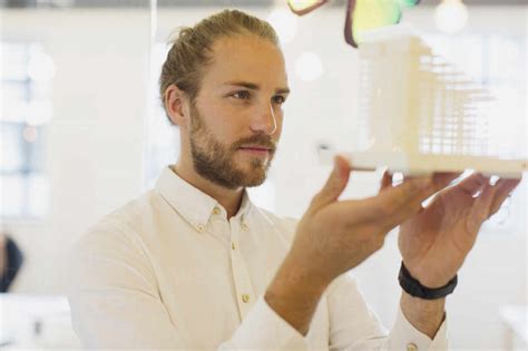 Focused Curious Male Architect Examining Model In Office Stock Photo