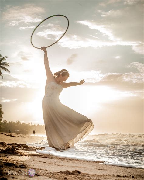 A Woman In A White Dress Is Playing With A Hula Hoop On The Beach