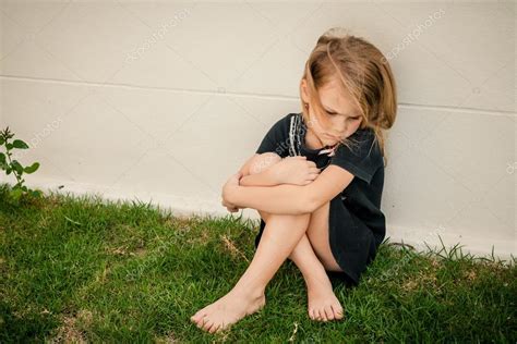 Portrait Of Sad Little Girl Sitting Near Wall In The Day Time — Stock