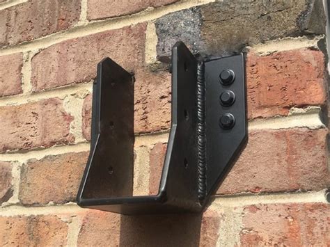 A Brick Wall With Two Black Brackets Attached To It S Side And One Is