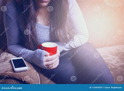 The Girl Is Sitting On The Couch And Drinking A Hot Drink Stock Image