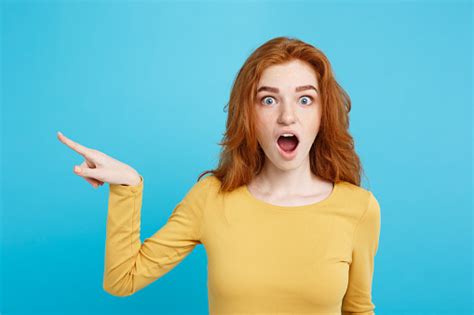 Fun And People Concept Headshot Portrait Of Happy Ginger Red Hair Girl With Pointing Finger Away