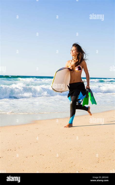 A Beautiful Girl Running At The Beach With Her Bodyboard Stock Photo