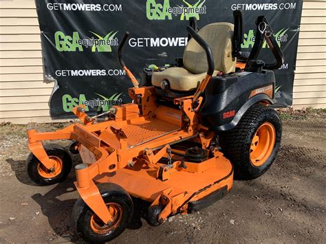 An Orange Lawn Mower Parked In Front Of A Sign That Says Getmowers Com