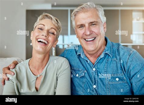 A Happy Relaxed Mature Retired Couple Talking And Laughing Together In The Living Room Smiling