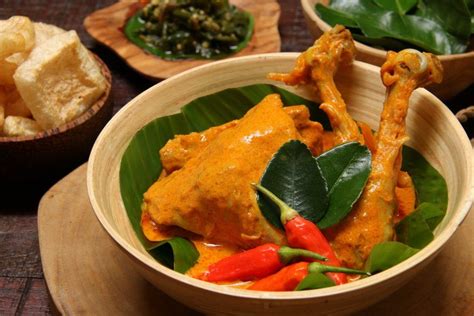 Sepiring Masakan Gulai Ayam Padang Dengan Sambal Hijau Di Belakangnya