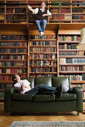 Two People Sitting On A Couch In Front Of Bookshelves